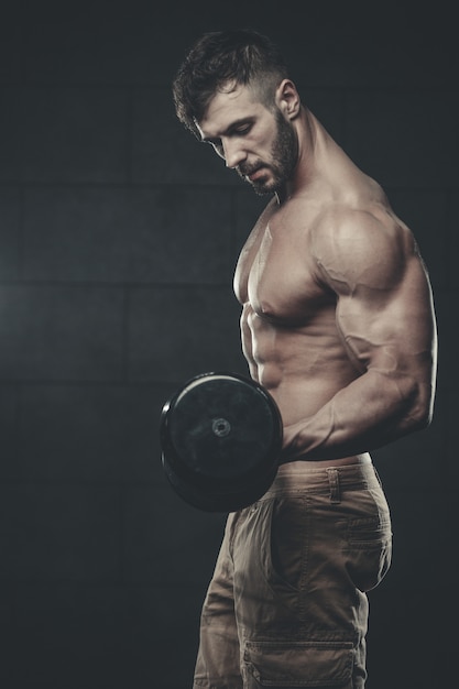 Photo beau modèle jeune homme formation bras dans la salle de gym