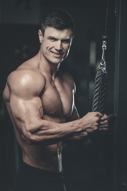 Beau modèle jeune homme formation bras dans la salle de gym