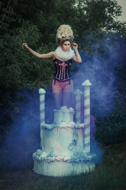 Photo beau modèle avec un maquillage créatif pose avec un gâteau géant