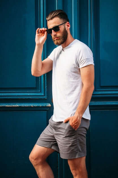 Beau modèle masculin hipster avec barbe portant un t-shirt blanc avec un espace pour votre logo ou design dans un style urbain décontracté