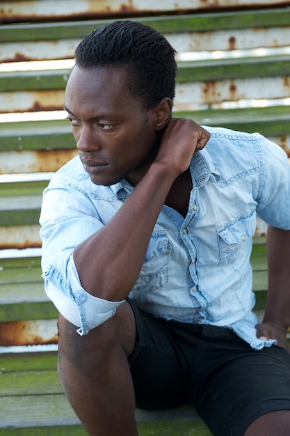 Photo beau modèle masculin noir assis à l'extérieur