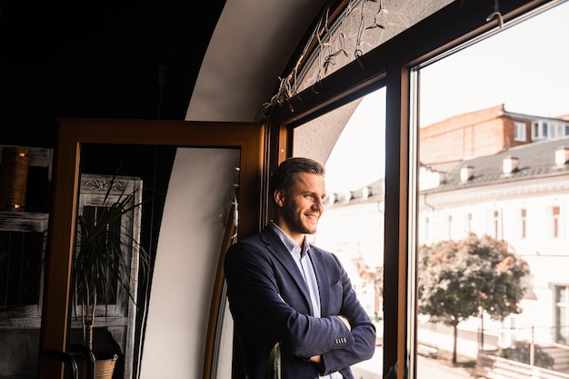 Beau modèle masculin pose au café. Un homme barbu portait un costume et souriait près de la fenêtre.