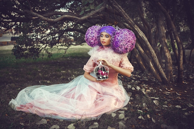 Beau modèle portant une robe rose pose dans une perruque créative