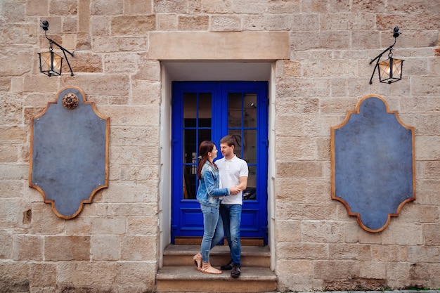 Un beau mur de briques et une porte bleue chic. un jeune couple debout à côté des portes