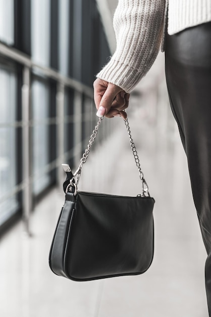 Beau nouveau sac noir élégant dans une dame élégante dans ses mains. Notion de style. Notion d'accessoires