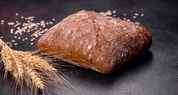 Beau pain brun en forme de carré savoureux sur un fond de béton foncé Cuisson du pain à la maison