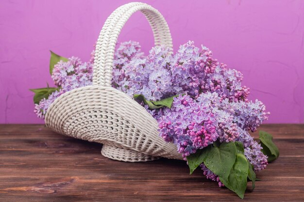 Beau panier en osier vintage blanc sur une table en bois Fleurs lilas dans un panier rétro