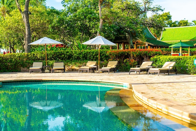 Photo beau parasol et chaise de luxe autour de la piscine extérieure de l'hôtel et du complexe avec noix de coco