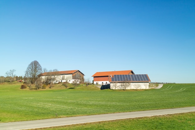 Beau paysage avec des bâtiments d'agriculture avec des panneaux solaires sur un toit sur un champs verts et des zones sur fond de ciel bleu propre dans un temps d'automne, l'Autriche.