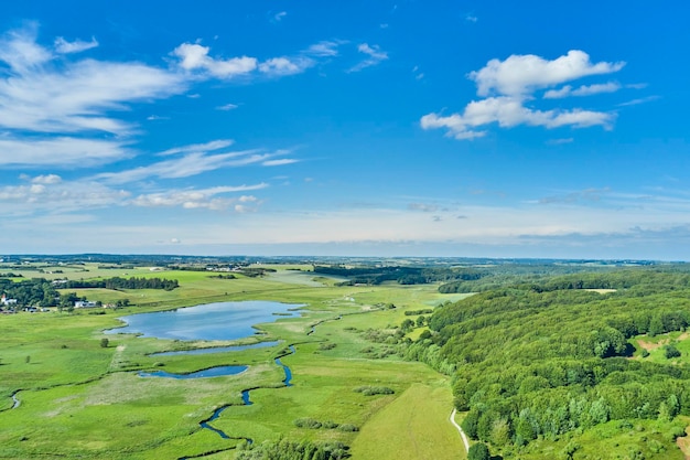 Beau paysage de campagne verdoyant et ouvert avec un lac d'herbe et des arbres entourant les maisons de ferme