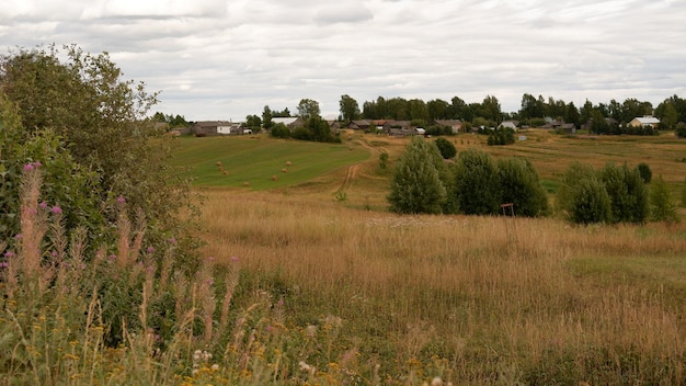 Beau paysage d'été rustique avec de vieilles maisons en bois et du foin sur le terrain