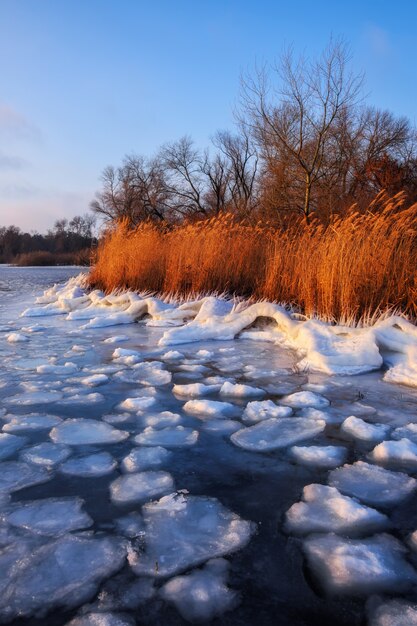 Beau paysage d'hiver avec lac gelé le matin avec lumière du lever du soleil