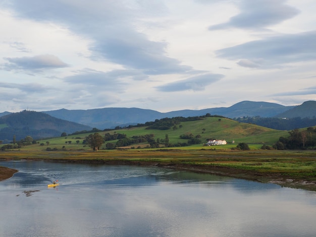 Beau paysage d'un lac réfléchissant avec un bateau sous un ciel nuageux