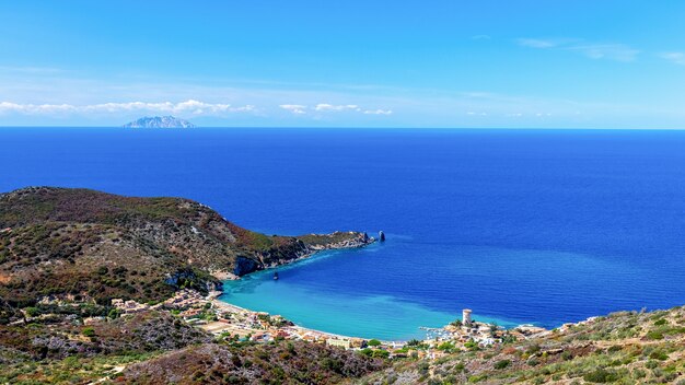 beau paysage marin avec plage et ville côtière avec un phare dans la baie île de Giglio