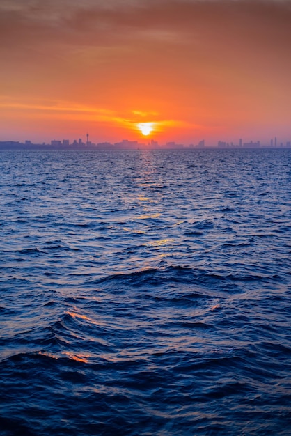 Beau paysage de mer bleue avec fond de ville skyline au lever du soleil