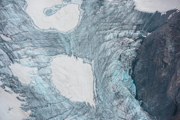 Beau paysage de montagne avec une langue glaciaire verticale avec des fissures parmi les rochers Toile de fond naturelle impressionnante d'un grand glacier avec cascade de glace Texture naturelle du glacier de montagne avec des fissures en gros plan