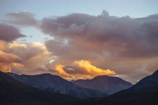 Beau paysage de montagne avec lumière d'aube dorée dans un ciel nuageux. Paysage de montagne pittoresque avec des couleurs lumineuses dans le ciel du coucher du soleil. Silhouettes de montagnes au lever du soleil. Or illuminant la lumière du soleil dans le ciel