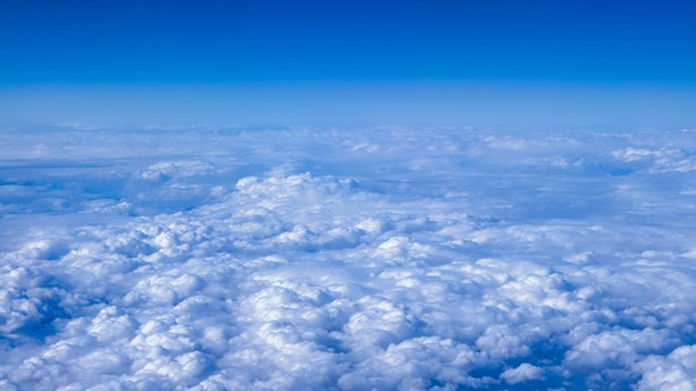 Beau paysage nuageux avec ciel bleu Magnifique panorama au-dessus des nuages blancs comme vu à travers la fenêtre d'un avion Voyageant par air concept