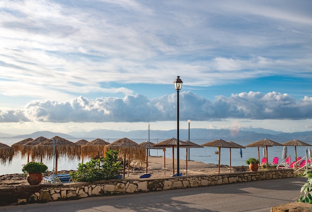 Beau paysage de la plage de la mer Ionienne avec des chaises longues colorées et des parasols en staw