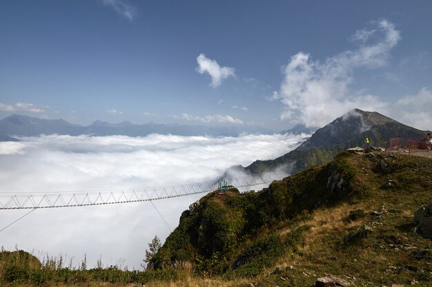 Photo beau paysage avec pont suspendu en montagne.