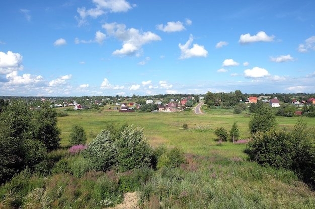 Beau paysage rural de campagne avec des maisons sur des collines au loin par une chaude journée d'été ensoleillée