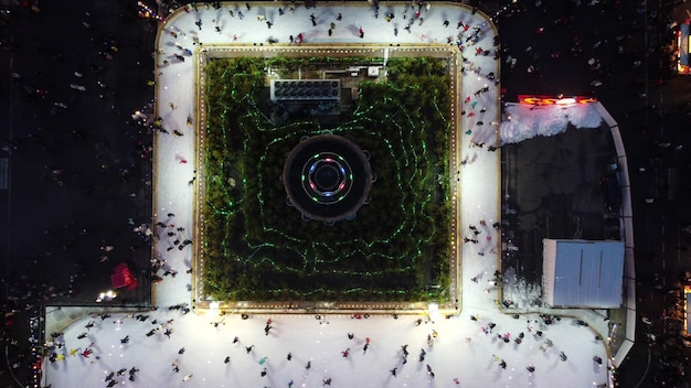 Beau paysage urbain de nombreuses personnes patinant sur une patinoire en plein air avec éclairage et guirlandes