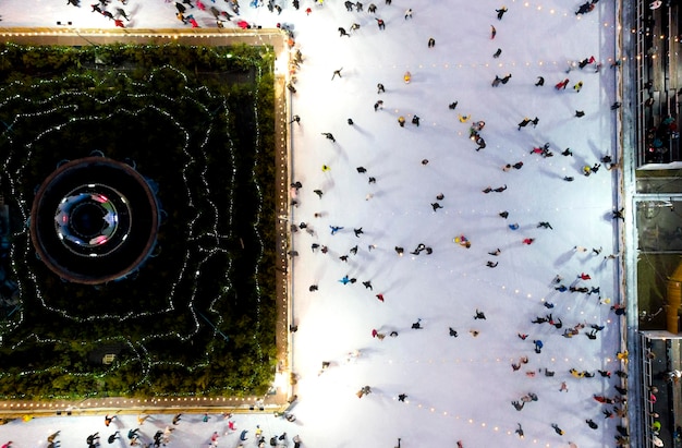 Beau paysage urbain de nombreuses personnes patinant sur une patinoire en plein air avec éclairage et guirlandes