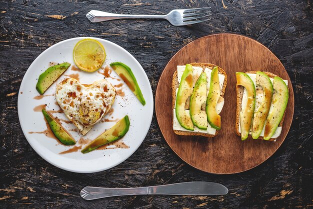 Un beau petit-déjeuner romantique sain d'oeufs au plat en forme de coeur sur une assiette blanche et sandwiches à l'avocat