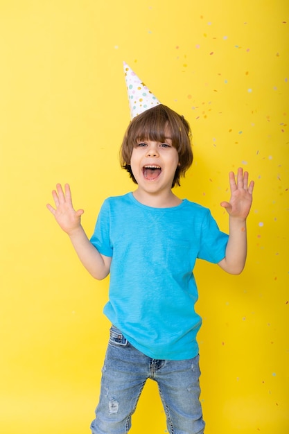 Beau petit garçon d'anniversaire en chemise bleue et chapeau avec des ballons fond jaune joyeux anniversaire