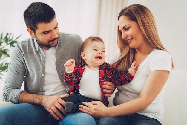 Beau petit garçon appréciant à la maison avec ses parents. Ils sont assis sur un canapé et s'amusent.