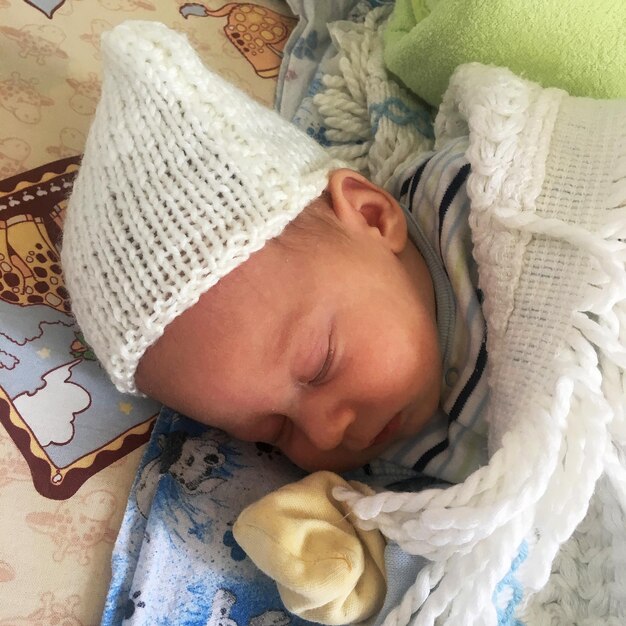 Beau petit garçon endormi avec un chapeau d'enfant posant un photographe pour une photo couleur