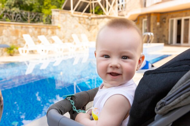 Beau petit garçon est assis dans une poussette au bord de la piscine. Mise au point sélective