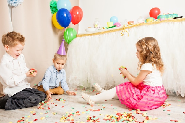 Beau petit garçon et fille jetant des confettis colorés sur la fête d'anniversaire