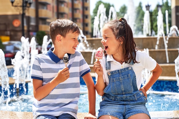 Beau petit garçon et fille mangeant des glaces en été