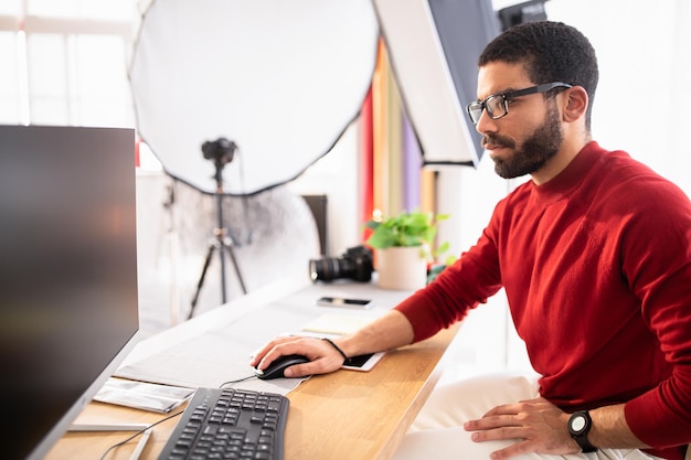 Beau photographe travaillant sur ordinateur au bureau