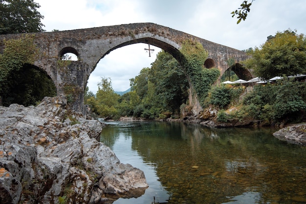 Photo beau pont romain situé à cangas de onis asturias à côté de la rivière sella un jour d'été