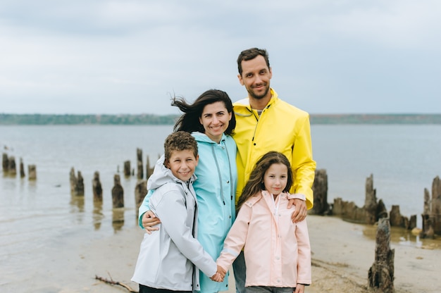 Beau portrait de famille vêtu d'un imperméable coloré près du lac