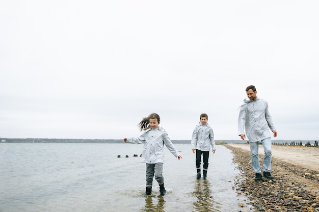 Beau portrait de famille vêtu d&#39;un imperméable près de la mer