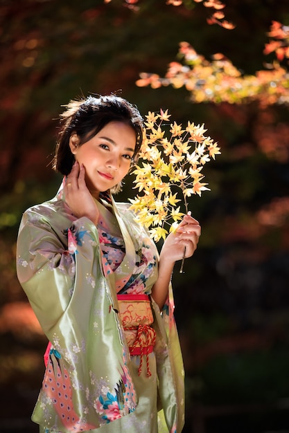 Beau portrait de femme asiatique portant un kimono d'or japonais dans le parc