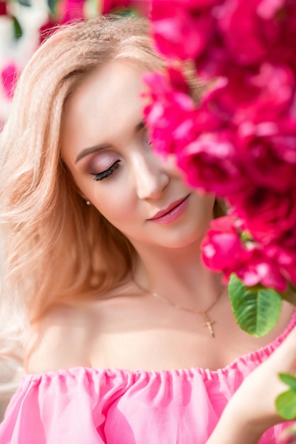 Beau portrait d'une femme blonde en roses roses. gros plan, maquillage, cils allongés