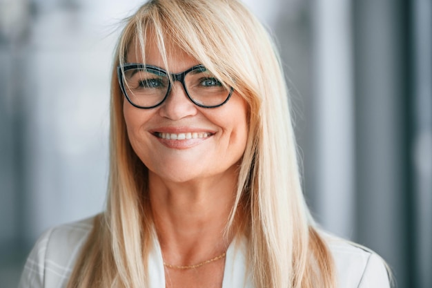 Beau portrait Femme en vêtements formels blancs se tient à l'intérieur