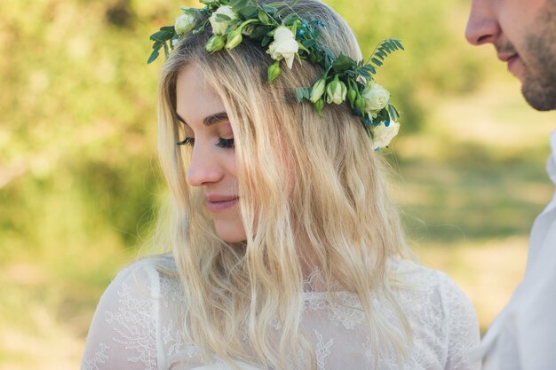 Beau portrait de femme vêtue d'une robe blanche de style bohème avec une couronne de fleurs en été