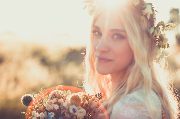 Beau portrait de femme vêtue d'une robe blanche de style bohème avec une couronne de fleurs en été