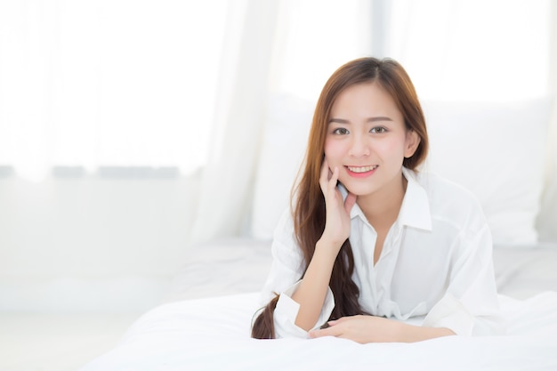 Beau portrait jeune femme asiatique couchée et sourire tout en se réveillant.