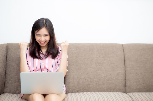 Beau portrait jeune femme asiatique excitée et heureuse du succès avec un ordinateur portable