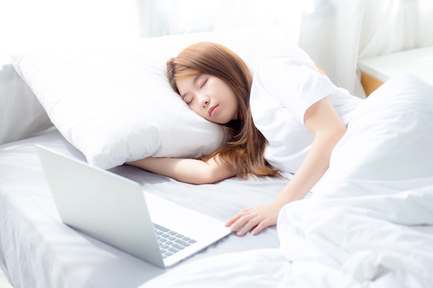 Beau portrait jeune femme asiatique avec ordinateur portable couché dans la chambre