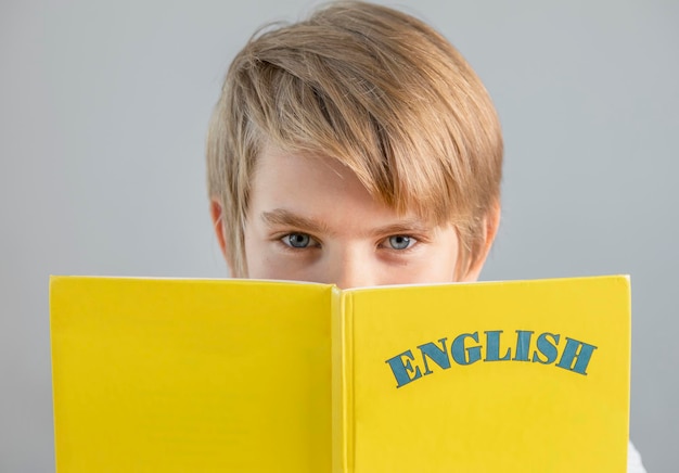 Beau préadolescent écolier tenant livre anglais jaune éducation moderne langues étrangères