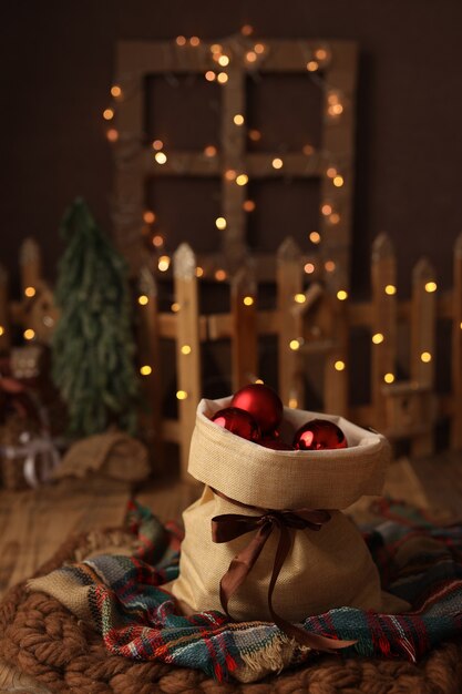 beau sac de Noël avec des cadeaux faits de boules rouges d'arbre de Noël sur un fond foncé