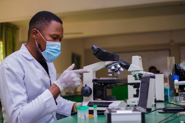 Beau scientifique masculin professionnel travaillant sur un vaccin dans un laboratoire de recherche scientifique pointant vers la recherche.