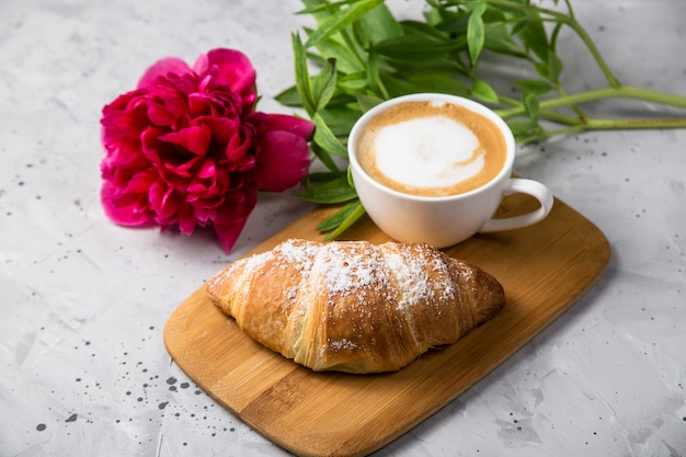 Beau et simple petit déjeuner français traditionnel de croissant frais et une tasse de cappuccino